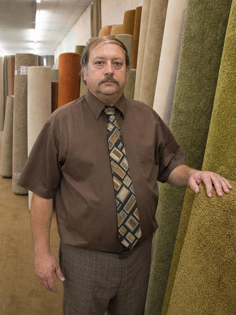 Carpet Man, eine fiktive Figur, zwischen Teppichrollen.