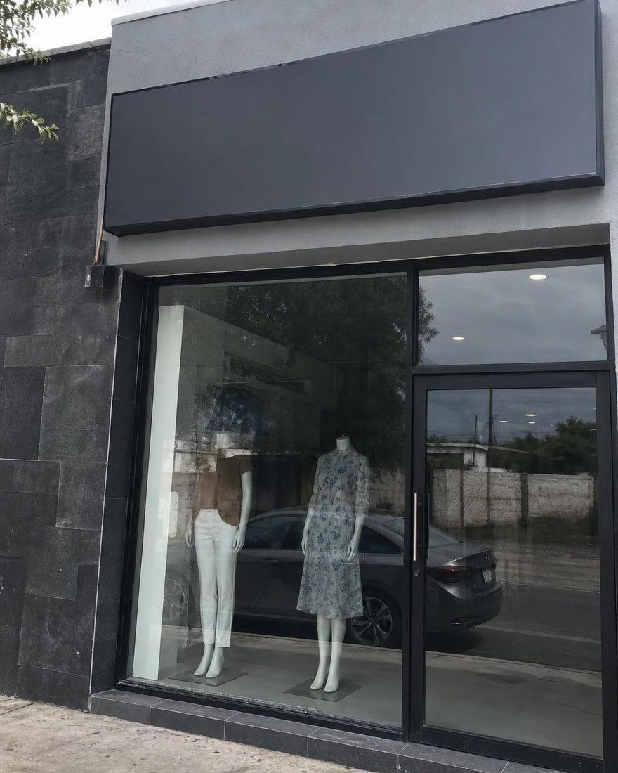 Handyfoto des Boutique-Schaufensters bei Tag mit flachem Licht und Spiegelungen