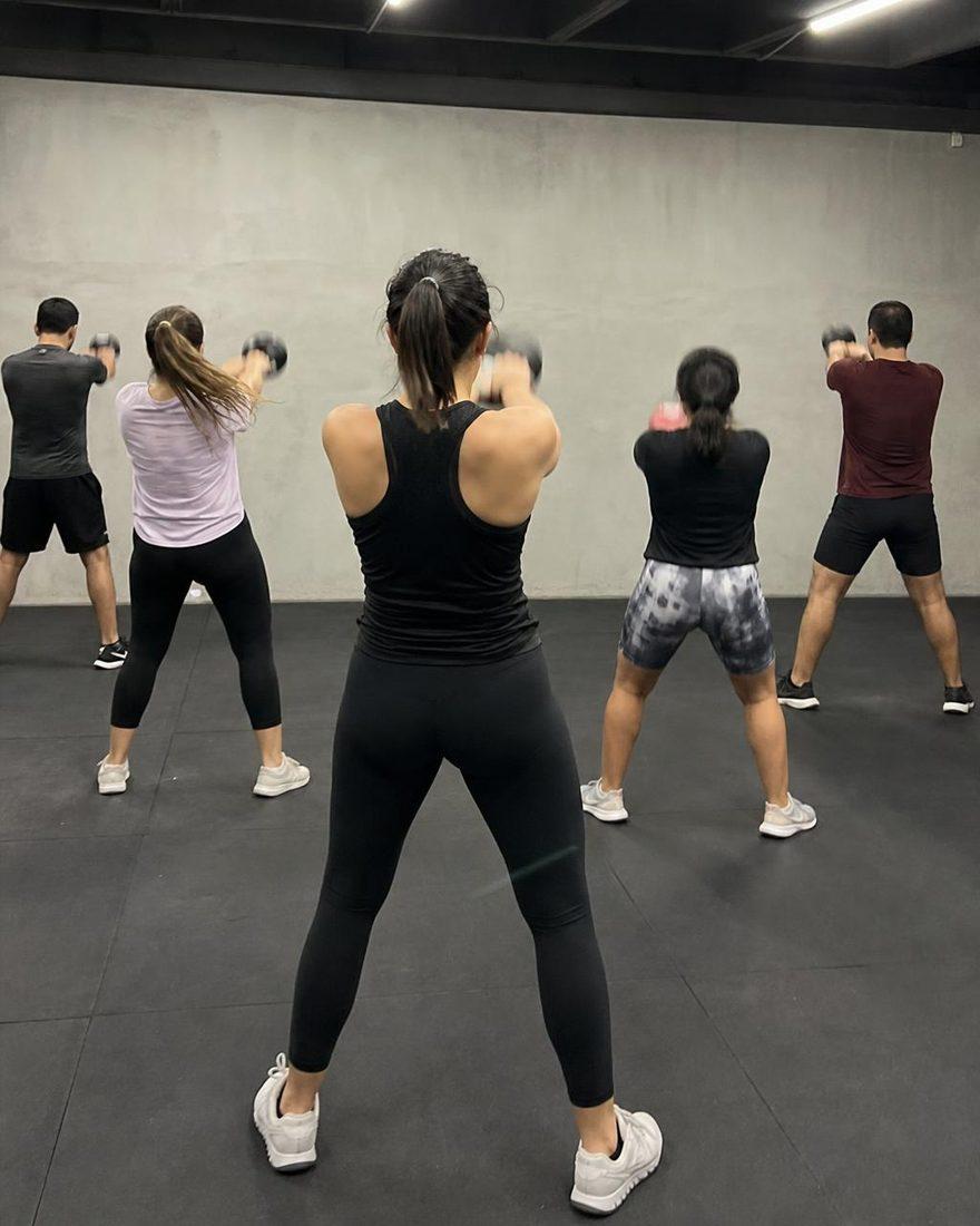 Foto de celular de una clase de grupo tomada desde atrás, entrenando con mancuernas