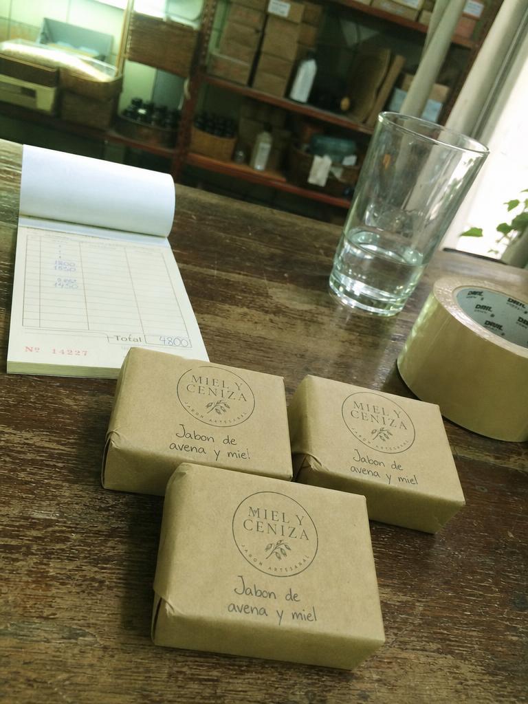 Phone photo of three soap bars wrapped in kraft paper on a wooden counter
