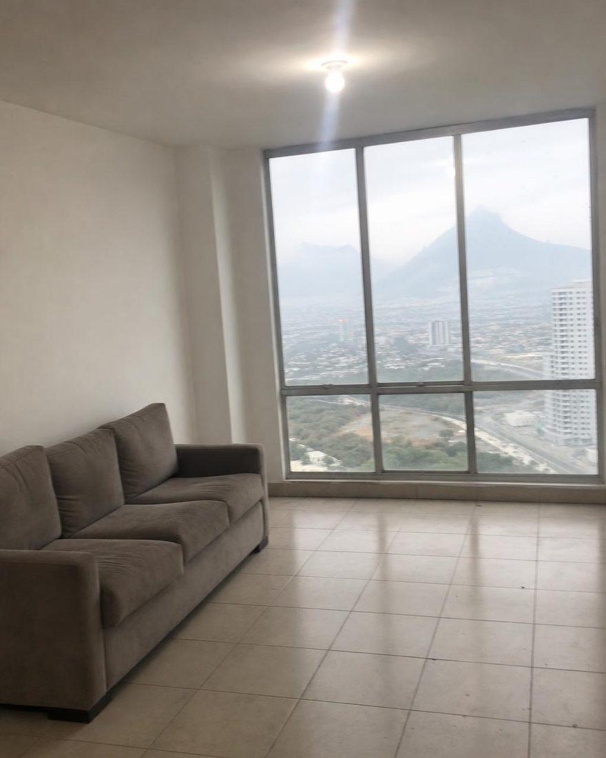 Phone photo of a nearly empty apartment with a large window and mountain view in flat light