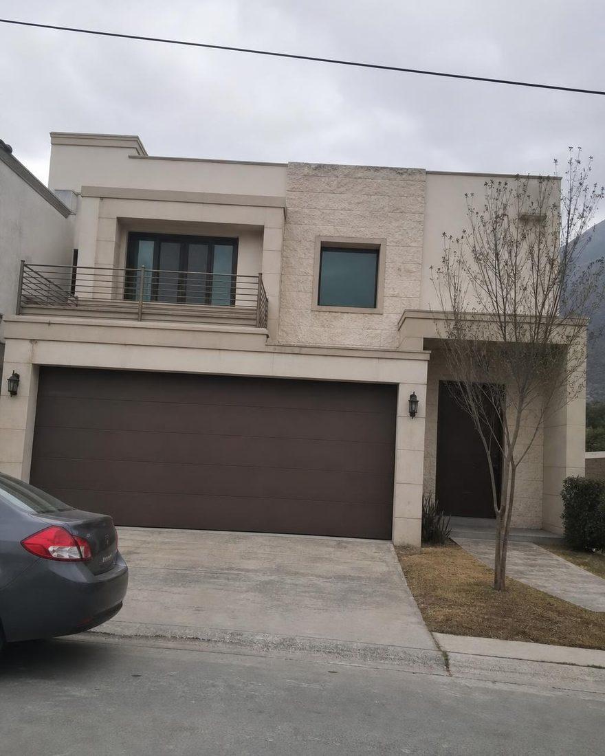Phone photo of a house exterior by day, with a car parked in front